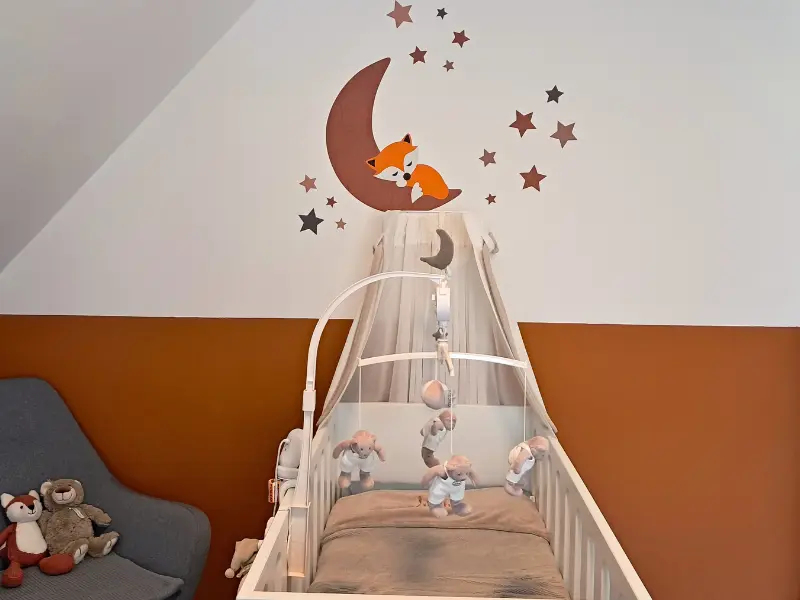 Mintgroene babykamer met een okergele maan en sterren behangsticker met een slapend vosje.